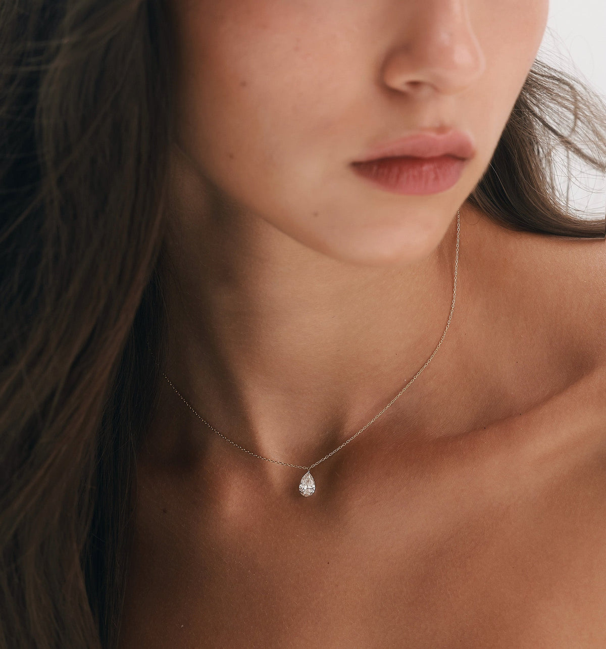 PEAR shape floating lab diamond necklace in rose gold styled with diamond earrings in curated ear composition on model